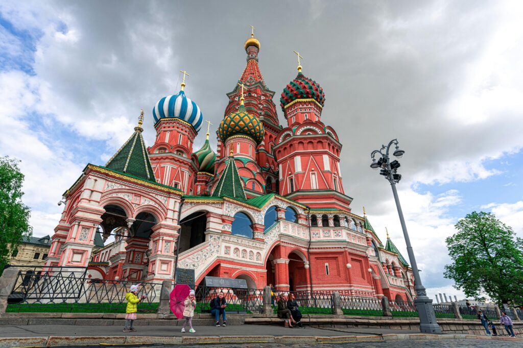 A vibrant view of Saint Basil's Cathedral, Moscow, captured under dramatic skies with tourists admiring its beauty.