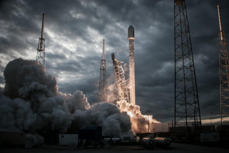 Low angle of cloudy launch of rocket after countdown from spaceport against dark gray sky